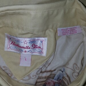 May include: A beige button-down shirt with a white label that says "Panhandle Slim" and a pink label that says "100% Cotton/Coton Style #2152263 Designed in Texas Made in Indonesia".