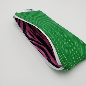 May include: A green zippered pouch with white polka dots and a pink and black zebra print lining.