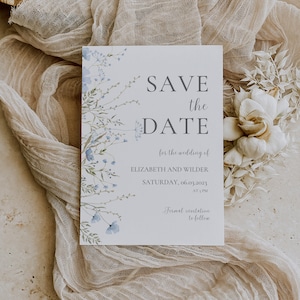 May include: Save the date card with a blue floral design. The card reads "Save the Date" for the wedding of Elizabeth and Wilder on Saturday, 06.03.2023 at 5 PM. Formal invitation to follow.