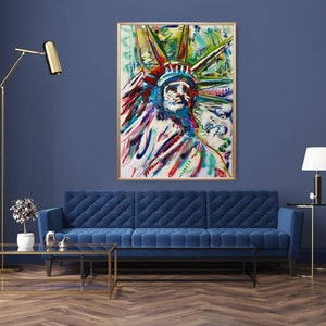 Puede incluir: Una pintura abstracta colorida de la Estatua de la Libertad, con un esquema de color azul, verde y amarillo. La pintura est&aacute; enmarcada en un marco dorado y est&aacute; colgada en una pared azul.