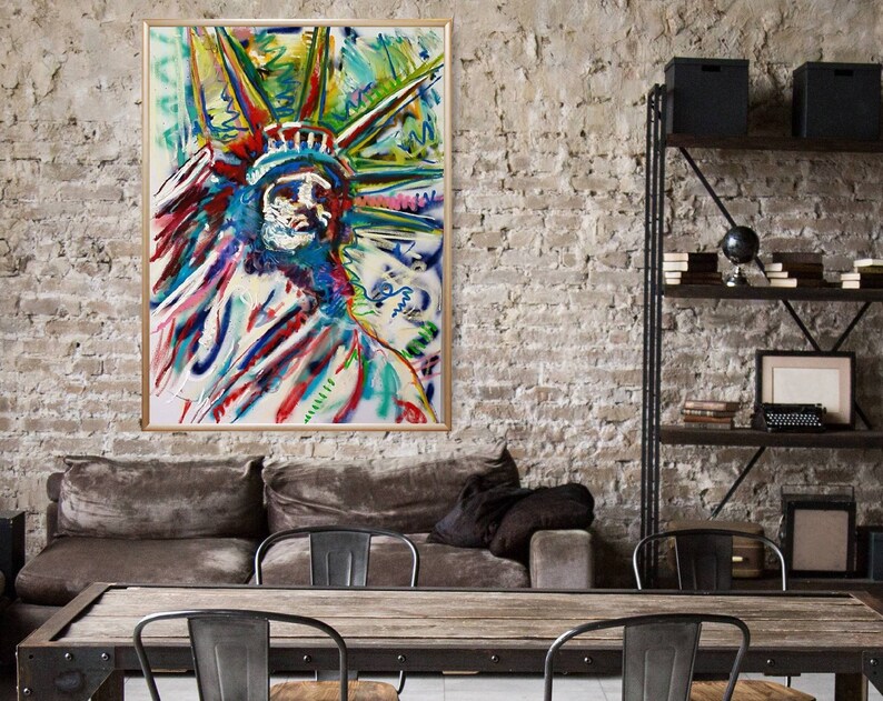 Puede incluir: Pintura abstracta de la Estatua de la Libertad en una variedad de colores, incluyendo azul, verde, rojo y amarillo. La pintura est&aacute; enmarcada y colgada en una pared de ladrillo.