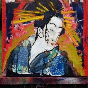 May include: A colorful abstract painting of a woman with a large, yellow and red headdress. The woman is wearing a blue and white patterned kimono. The painting is on a canvas and is displayed on an easel.