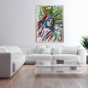 Puede incluir: Pintura abstracta de la Estatua de la Libertad en una variedad de colores, incluyendo azul, verde, rojo y amarillo. La pintura est&aacute; enmarcada en un marco de madera y est&aacute; colgada en una pared blanca en un sal&oacute;n.
