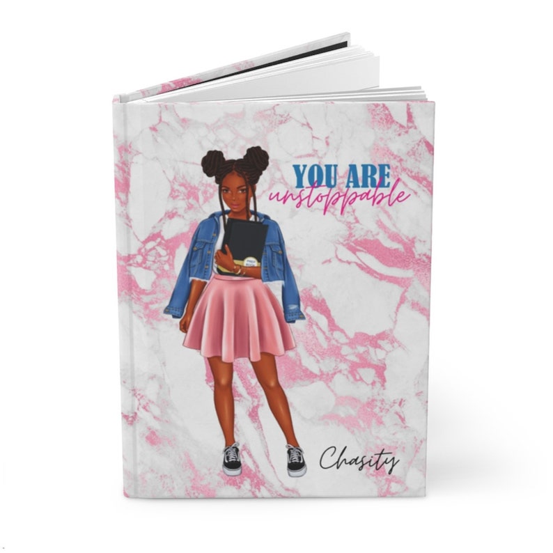 May include: Hardcover journal with a pink marble design and the text "YOU ARE unstoppable". The cover features an illustration of a person in a denim jacket, pink skirt, and sneakers. The name "Chasity" is written at the bottom.