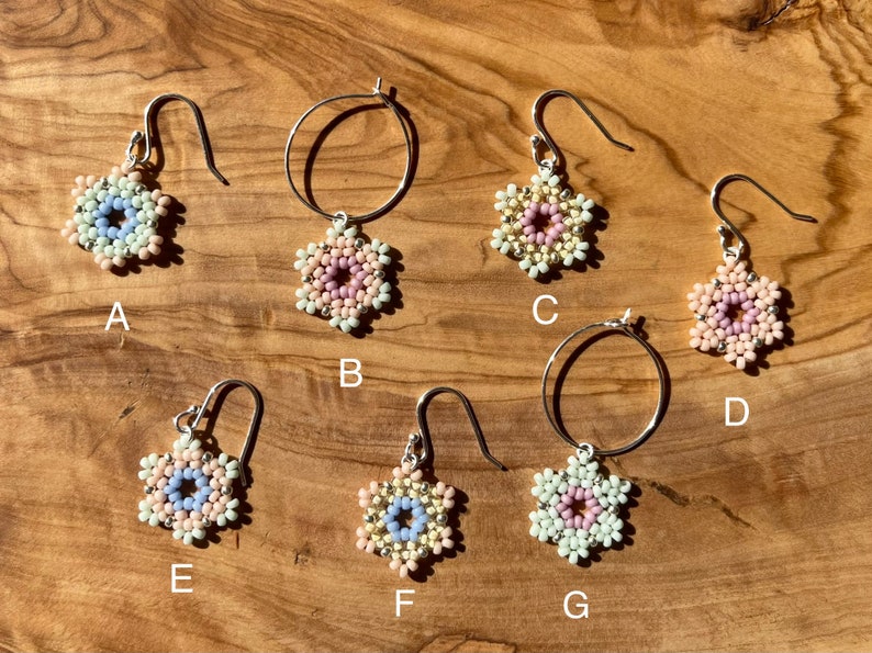 Puede incluir: Siete pares de pendientes de cuentas con un dise&ntilde;o de flor. Los pendientes est&aacute;n hechos con cuentas blancas, rosas y azul claro. Algunos pendientes tienen un dise&ntilde;o de aro, mientras que otros tienen un dise&ntilde;o de gota.