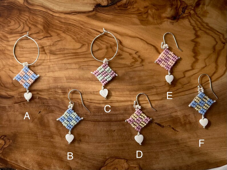 Puede incluir: Seis pares de pendientes con una variedad de colores y estilos. Cada pendiente presenta un peque&ntilde;o amuleto de forma cuadrada con una cuenta en forma de coraz&oacute;n que cuelga de &eacute;l. Los pendientes est&aacute;n etiquetados de la A a la F.