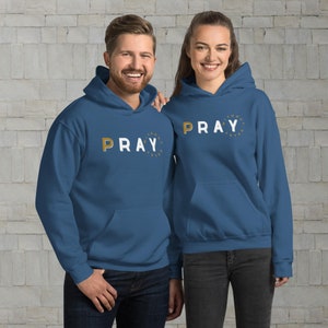 May include: Two people wearing blue hoodies with the text "Pray Without Ceasing" in gold lettering on the front.