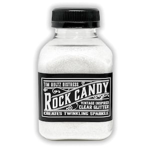 Könnte beinhalten: Eine transparente Plastikflasche gefüllt mit weißem Glitzer, mit einem schwarzen Deckel. Das Etikett lautet "Tim Holtz Distress Rock Candy Vintage Inspired Clear Glitter Creates Twinkling Sparkle."