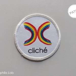 May include: A white circular patch with a rainbow-colored X design and the word "cliché" in black text.