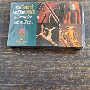 May include: A CD sampler titled "The Sound And The Spirit" with a history of music at the Olympic Games. The cover features images of musical instruments, a gymnast, and the Atlanta 1996 Olympic logo.