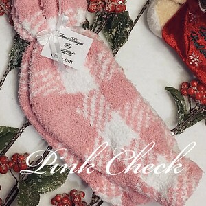 May include: Pair of pink fuzzy slipper socks with a white snowflake pattern. The socks are tied together with a white ribbon and a tag that reads "Sweet Designs by K&M".