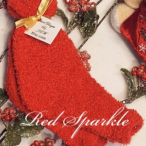 May include: Red fuzzy socks with sparkly threads. The socks are tied with a gold ribbon and a white tag that says "Love Designs Etsy.com".