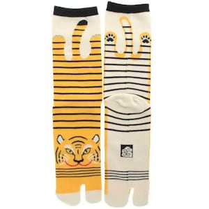 May include: Split-toe socks with a tiger design. One sock shows a tiger face, the other tiger paw prints. The socks are yellow with black stripes and accents, and white toes and heels.