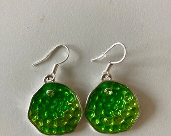 May include: A pair of green and silver earrings with a textured, honeycomb-like design. Each earring has a small, clear rhinestone in the center.