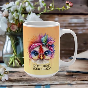 May include: White ceramic mug featuring a colourful illustration of a chicken wearing glasses and a headband. The text "Don't hide your crazy!" is printed on the mug.