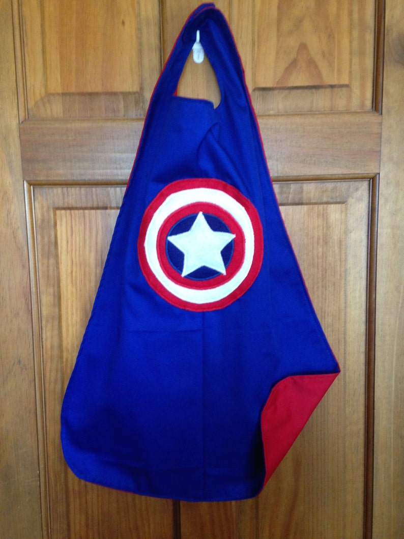May include: A blue superhero cape with a red trim and a white star on a red, white and blue circle in the centre.
