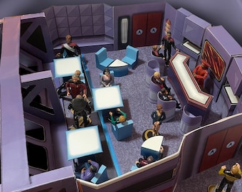 May include: A model of a Star Trek starship bridge set with multiple figures of crew members in various poses. The bridge is made of cardboard and features a command console, seating, and a viewscreen. The figures are painted in a variety of colors and are wearing Star Trek uniforms.
