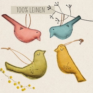 Könnte beinhalten: Vier handgefertigte Filzvogel-Ornamente in Rosa, Blau, Gelb und Grün. Jeder Vogel hat ein einfaches gesticktes Design und eine Schlaufe zum Aufhängen. Der Text "100% LEINEN" ist in der oberen linken Ecke des Bildes sichtbar.