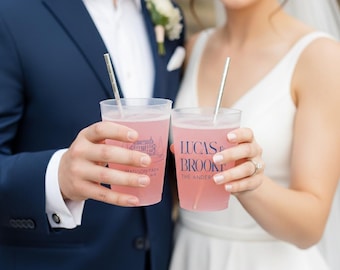 May include: Two translucent frosted plastic cups filled with a pink beverage, each containing a silver straw. One cup features the text LUCAS & BROOKE THE ANDERSONS in navy blue, while the other displays a line drawing and Madison Park WA text.