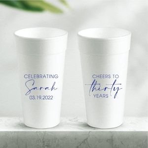 May include: Two white foam cups with blue text. One cup says "Celebrating Sarah 03.19.2022". The other cup says "Cheers to thirty years".
