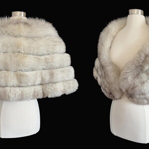 May include: Two views of a luxurious, light gray fur stole. The stole is displayed on a white mannequin, showcasing its layered design and soft texture. The background is a solid black, highlighting the elegance of the garment.