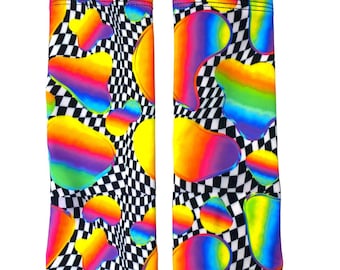 May include: A pair of colorful leg warmers with a rainbow and checkered pattern. The leg warmers are made of a stretchy fabric and have a snug fit.