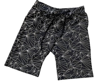May include: Black shorts with a white geometric pattern. The shorts have a drawstring waistband and a relaxed fit. The geometric design features a network of interconnected lines, creating a modern and stylish look. These shorts are suitable for casual wear.