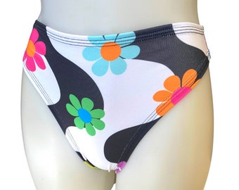 May include: Black and white swimsuit with a psychedelic floral print featuring colorful flowers with yellow, orange, pink, green, and blue accents.