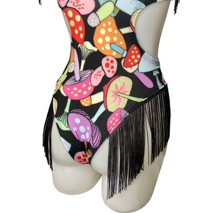 Puede incluir: Traje de ba&ntilde;o negro con ribete de flecos y estampado de setas de colores.
