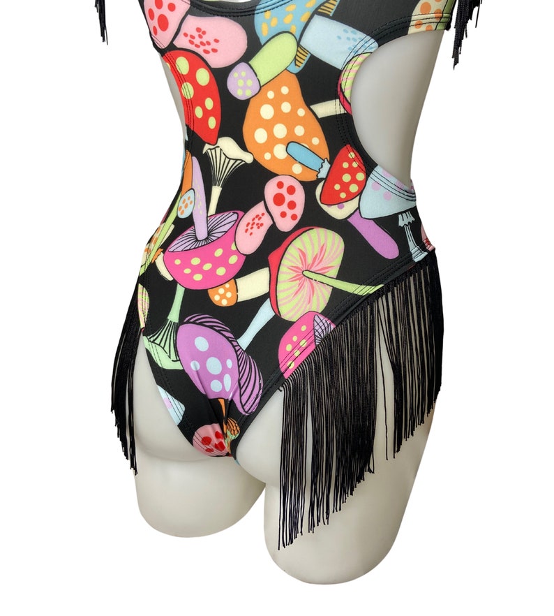 Puede incluir: Traje de ba&ntilde;o negro con ribete de flecos y estampado de setas de colores.