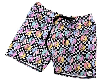 May include: Black and white checkered swim shorts with a pastel yin yang pattern. The shorts have a drawstring waist and a small logo patch on the bottom right corner.