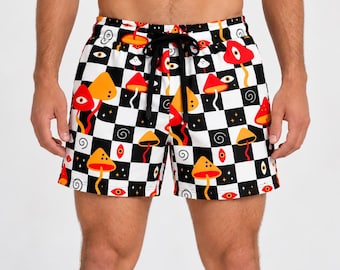 May include: Shorts featuring a black and white checkered pattern with a repeating graphic print of orange and red mushrooms, stylized eyes, and small black swirls. The shorts include a black drawstring at the elasticized waistband.