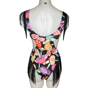 Puede incluir: Traje de ba&ntilde;o negro con estampado de setas de colores y ribete de flecos negros. El traje de ba&ntilde;o tiene recortes en los lados.