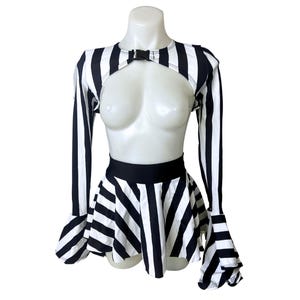 May include: Black and white striped crop top with long sleeves and a black buckle detail. The top is paired with a matching black and white striped skirt with a flared hem.