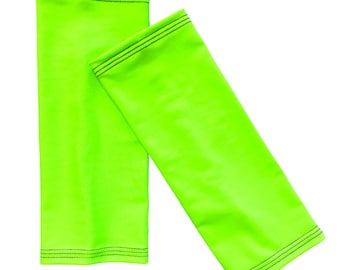 Könnte beinhalten: Zwei leuchtend grüne Armwärmer mit schwarzen Nähten. Die Armwärmer sind aus einem dehnbaren, glatten Stoff.