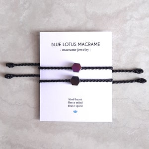 May include: Two black macrame bracelets with iridescent hexagonal beads. The card reads "Blue Lotus Macrame - macrame jewelry - kind heart fierce mind brave spirit".