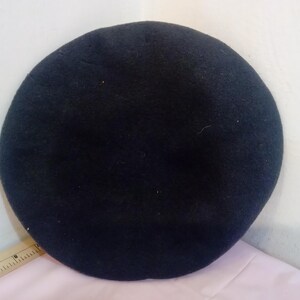 May include: A black felt beret. The beret is a classic style hat.