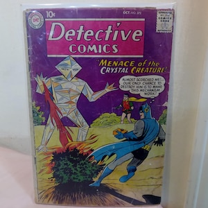 May include: A vintage comic book cover featuring Batman and Robin fighting a crystal creature. The cover is purple and features the text "Detective Comics" and "Menace of the Crystal Creature!"
