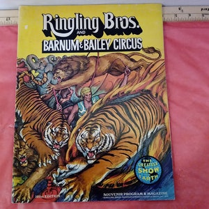 Peut inclure: Une couverture de programme vintage du cirque Ringling Bros. et Barnum & Bailey avec une illustration colorée de tigres, un lion et un homme en pagne. Le texte "The Greatest Show On Earth" est visible dans un cercle sur la couverture.
