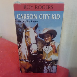 Puede incluir: Una cinta VHS con Roy Rogers en la película "Carson City Kid". La portada presenta una foto a color de Roy Rogers a caballo.