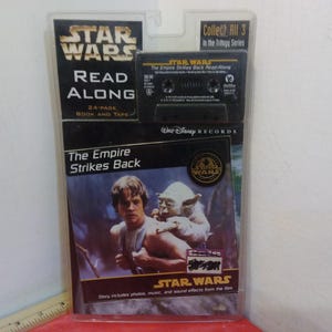 May include: A Star Wars Read Along book and cassette tape featuring Luke Skywalker and Yoda from The Empire Strikes Back. The cover features a photo of Luke Skywalker carrying Yoda on his shoulders. The text on the cover reads "Star Wars Read Along, The Empire Strikes Back, 24-page book and tape, Collect All 3 in the Trilogy Series".