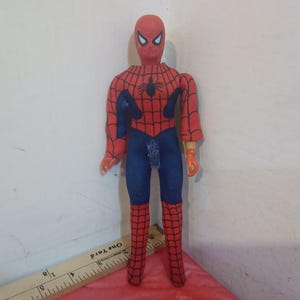 May include: A red and blue Spider-Man action figure with a black spider logo on the chest. The figure has a red mask with white eyes and is posed with arms outstretched.