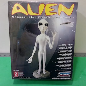 May include: Sealed plastic model kit of an alien figure. The box reads "ALIEN" and "Unassembled Plastic Model Kit." The alien figure is gray with large eyes and is standing on a circular base. Measures 7 3/4 inches (19.6 cm) assembled.