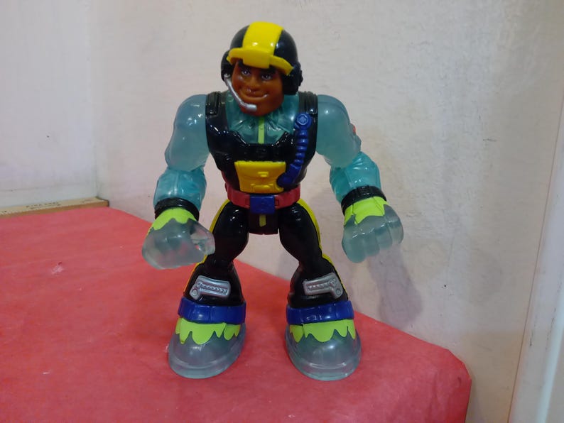 May include: A translucent blue action figure with a yellow helmet, black and red suit, and a black microphone. The figure has a black and blue belt and yellow and green boots.