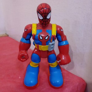 May include: A red and blue action figure of Spider-Man with a web shooter on his arm. The figure has a red and blue suit with a yellow belt and a black spider logo on the chest.