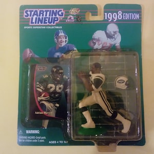 May include: A 1998 Starting Lineup Sports Superstar Collectibles action figure of Adrian Murrell, a football player wearing a green and white uniform. The figure is in a running pose with a football in his hand. The figure is packaged in a plastic blister pack with a green and white card featuring a photo of Murrell and the text "Adrian Murrell". The card also includes the Starting Lineup logo and the text "1998 Edition".