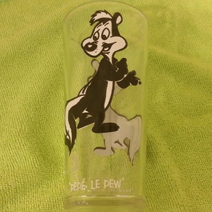 Puede incluir: Un vaso transparente con una ilustración de dibujos animados de Pepe Le Pew, un personaje de mofeta, en blanco y negro. El vaso tiene las palabras "PEPE LE PEW" impresas en la parte inferior. La mofeta se muestra en una pose juguetona. El vaso es cilíndrico.