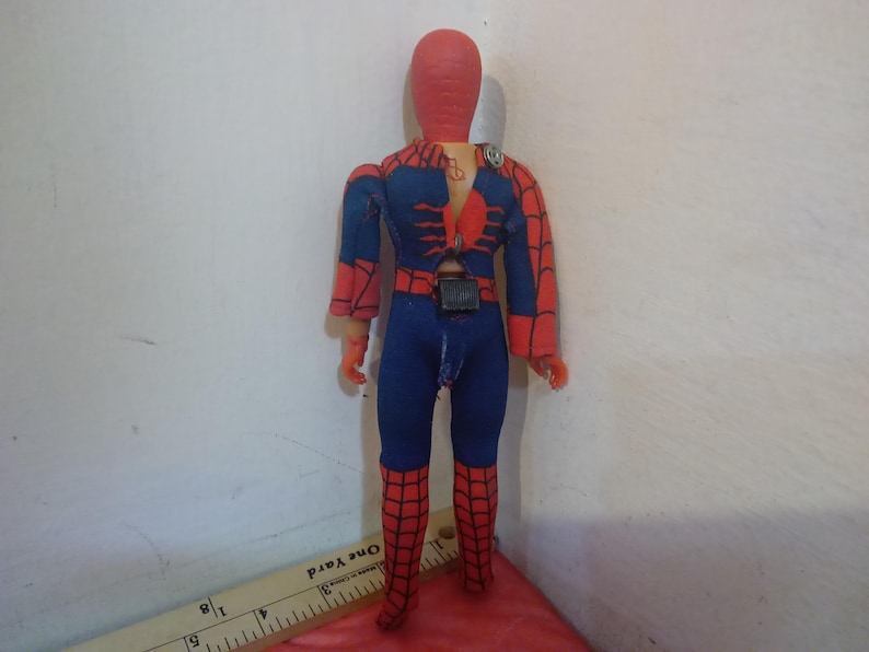 May include: A red and blue action figure of Spider-Man with a web design on the chest and legs. The figure has a red head and a black belt.