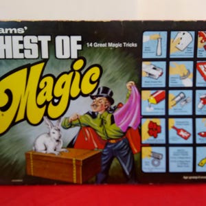 Op de afbeelding: Vintage "Chest of Magic" doos. De doos toont een goochelaar met een konijn, een kist en de woorden "Chest of Magic" in grote gele letters. Bevat 14 geweldige goocheltrucs.