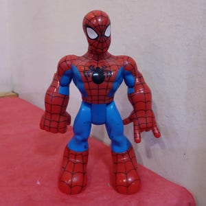 May include: A red and blue plastic action figure of Spider-Man. The figure has a black spider logo on the chest and a red and blue mask.